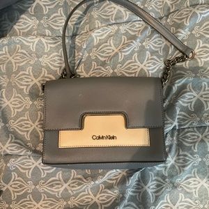 Calvin Klein blue and grey bag with a tan cross body strap and has dark metal